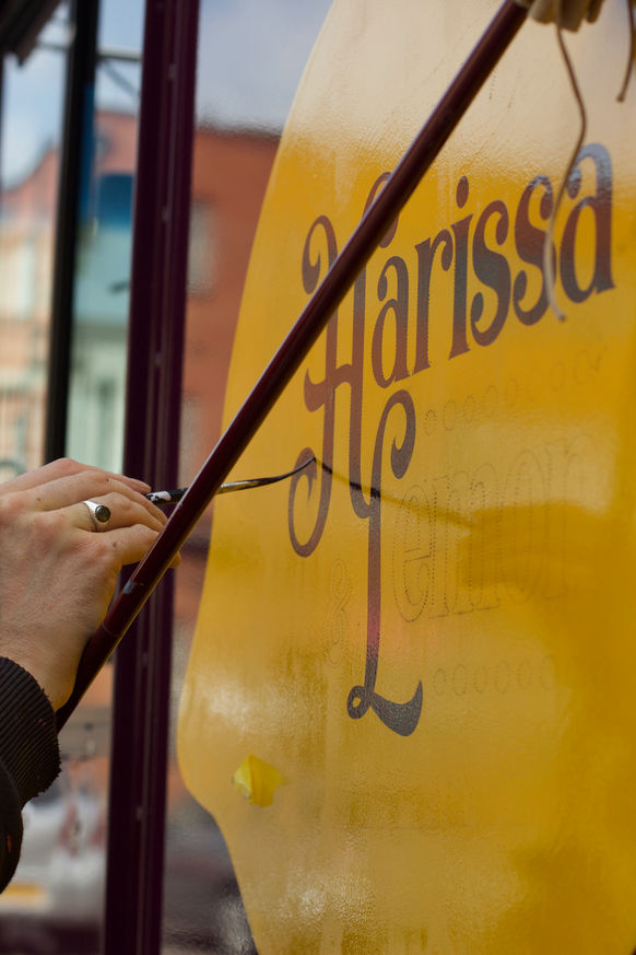 Signwriter hand painting the signage on a food truck