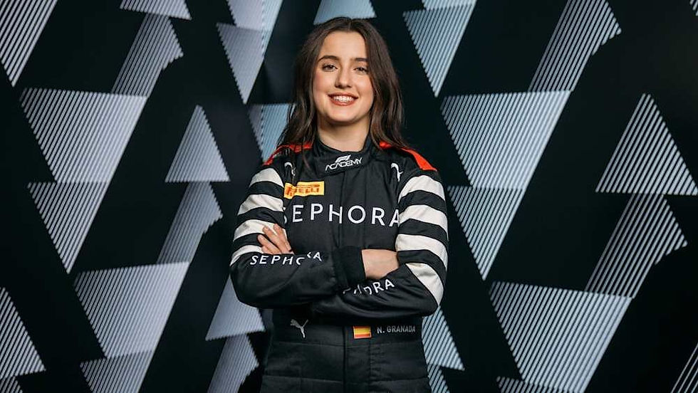 Smiling person in a black racing suit with "Sephora" on the front, arms crossed. Background features bold black and white geometric patterns.