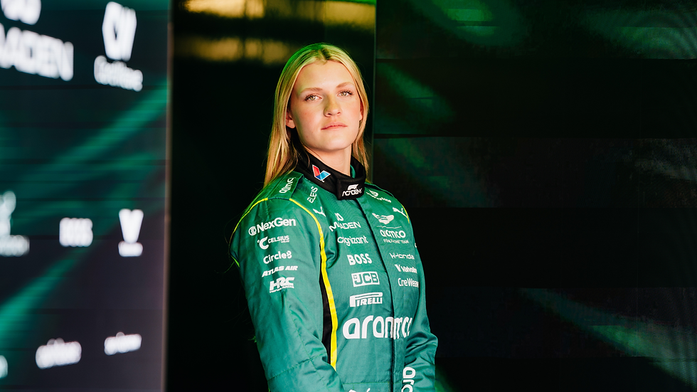 A racing driver in a green race suit looks at the camera. The mood is serious and calm.