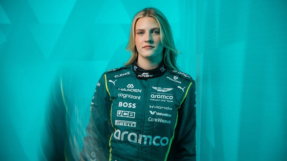 Race car driver in a green and black racing suit stands against a teal geometric background. Various sponsor logos are visible on the suit.