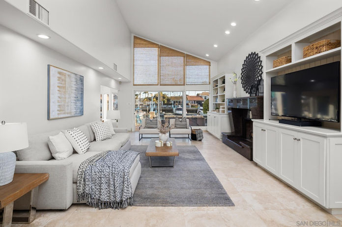 Green Turtle Rd, Coronado - large cream sofa with a chaise on the left wall with a gray rug underneath, across from white paneled TV media center on the right wall