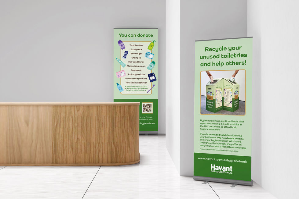 Image of two roller banners promoting the Community Hub hygiene banks in an open plan room with a reception desk.