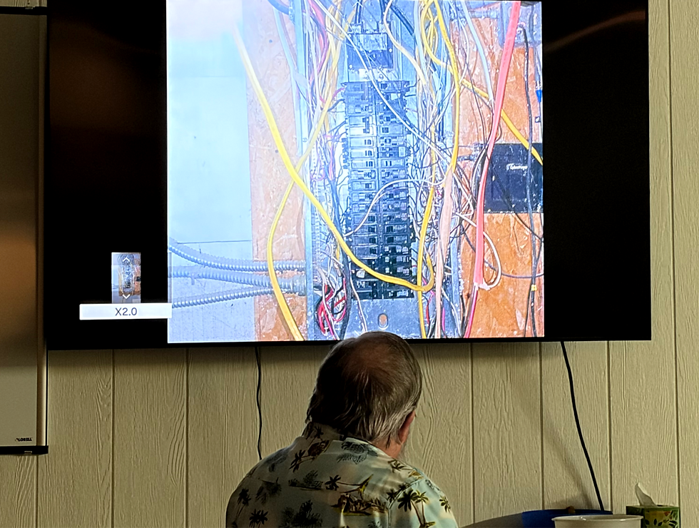 Councilmember Ed Smith views a photo of an improperly wired electrical panel.