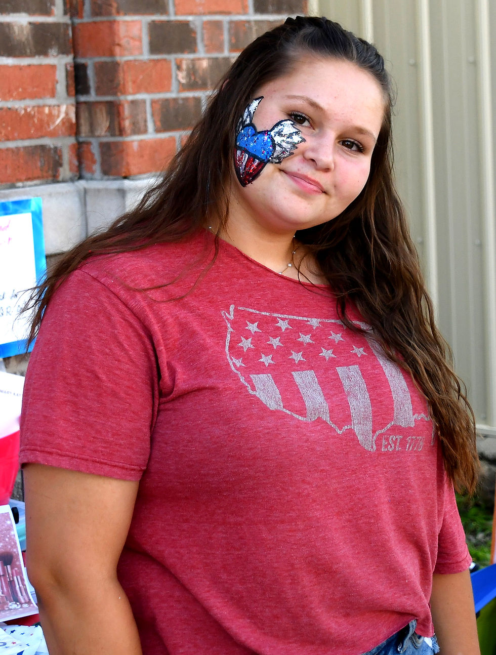 Wearing an "Est. 1776" t-shirt and a patriotic heart with angel wings in memory of her grandmother, Jaycee Henry is ready for Pleasanton's Stars and Stripes celebration. (Photos by Billy Roudybush / Linn County Journal)