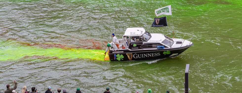 Guinness speed boat aids by releasing stream of bright green dye during the dyeing of Chicago River