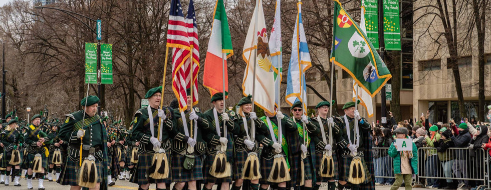 Flag bearers from Shannon Rovers Irish Pipe Band marches at front as St. Patrick's Day Parade begins