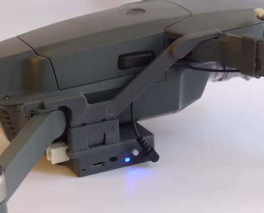 DJI Mavic 3 drone can be seen here sitting idle on a white table  with side view where attached sensors for payload release and drop from drone sky hook can be seen