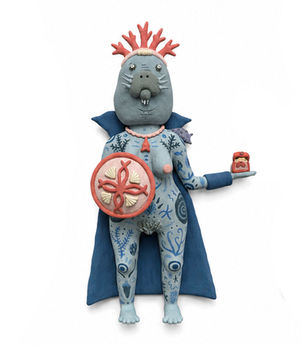 Manatee-headed ceramic figure with blue marine markings, a coral-shaped crown, shield, and open treasure chest.