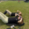 Two girls relaxing on grass, wearing riding attire
