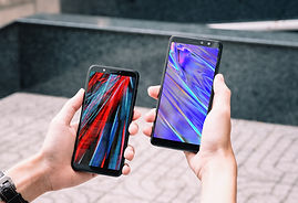 Two smartphones held in hands next to each other, being compared