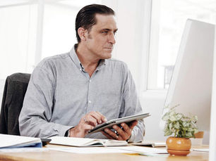 Homem olhando para o computador e teclando no tablet