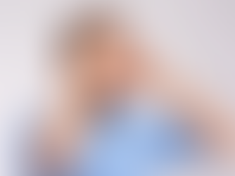 Man in a blue denim shirt holds his head with both hands, expressing stress or worry. Gray background enhances the tense mood.