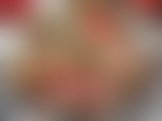 Brown gifts with red twine on festive patterned fabric. Background of red, white, and gold decorations enhances a warm, holiday atmosphere.