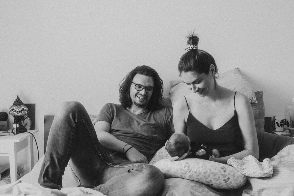 Vater, Mutter und Baby kuscheln zusammen im Bett