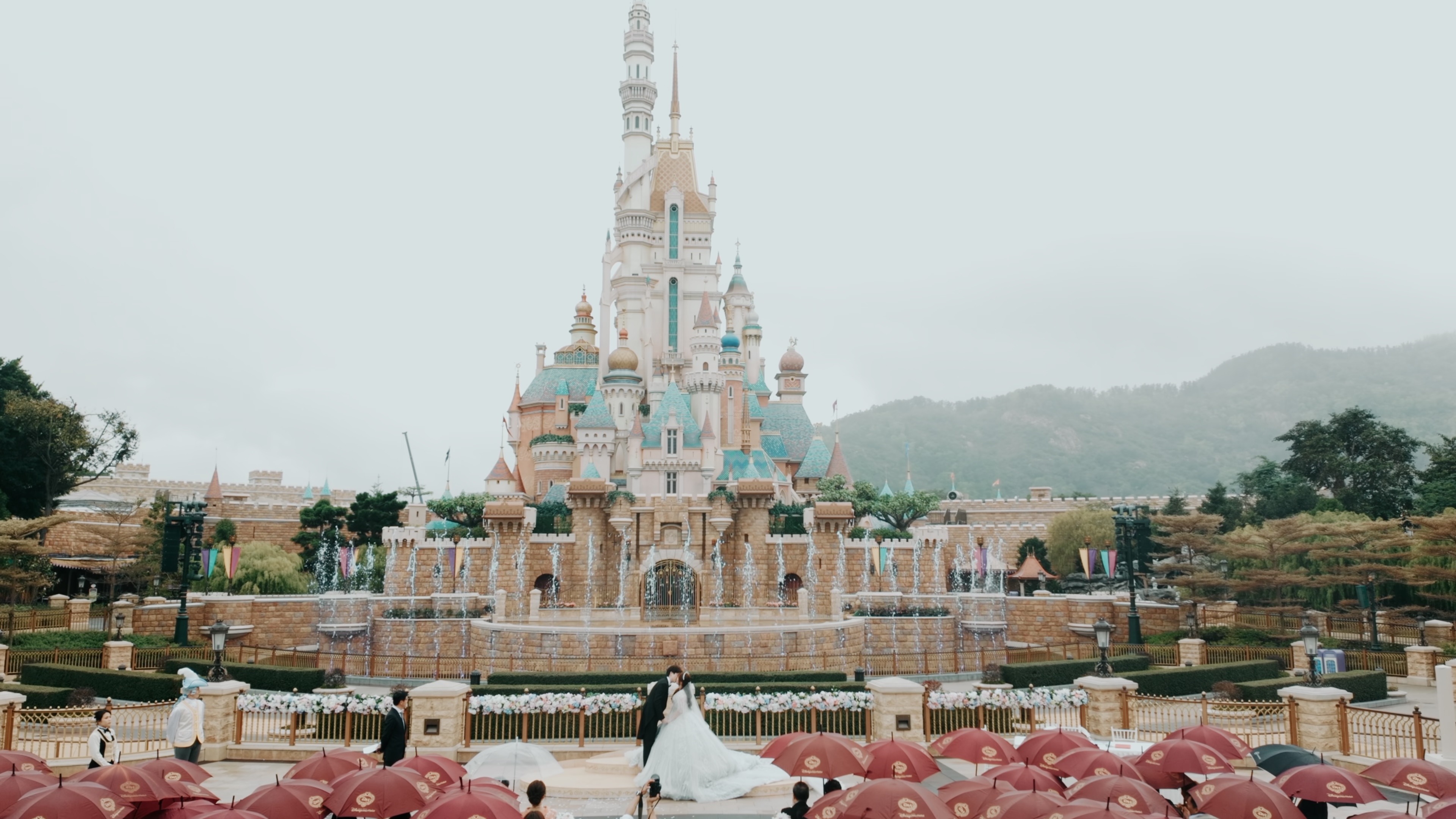 A couple kissing at their outdoor wedding ceremony in front of Hong Kong Disneyland's castle