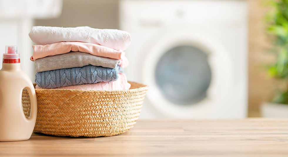 Folded laundry and detergent on a counter with washing machine
