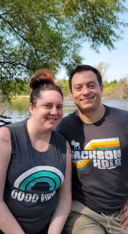 a man an woman pose for a photo in nature by a pond
