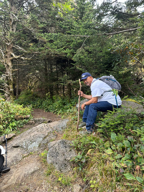 Man resting on a rock with a walking stick