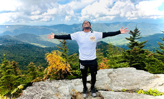 Man on mountain peak with arms outstretched