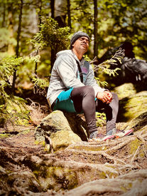 Man resting on a mossy rock in a sunlit forest