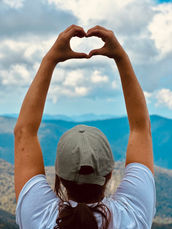 Hands forming heart shape over mountain landscape