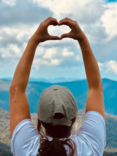 Hands forming heart shape over mountain landscape