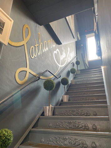 hand painted mural slogan on wall going up the stairs in shop