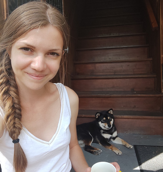 Une éducatrice assise au premier plan, avec son chien shiba inu en arrière plan