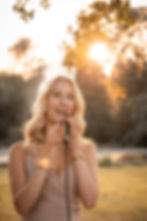 Antonia Brosch, gefühlvolle Hochzeitssängerin in NRW, performt bei Sonnenuntergang mit Mikrofon während einer emotionalen Hochzeitsfeier.