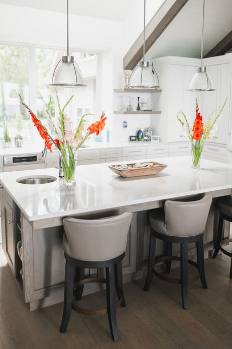 Large kitchen island with a quartz top, three pendant lights and grey swivel stools