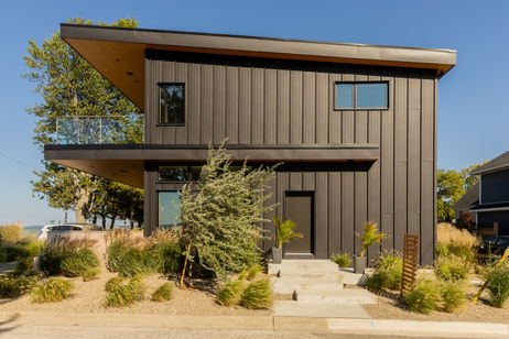 Modern black steel-sided custom home in Bright’s Grove with a wood soffit overhang and glass balcony