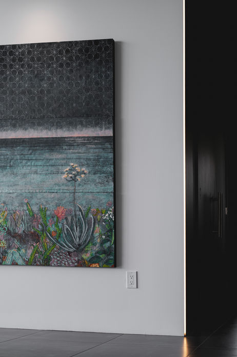 Colourful seascape painting on a white wall beside a door with a hidden LED light strip