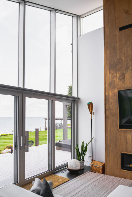 Tall sliding doors under clerestory windows looking out to a deck, hot tub and Lake Huron