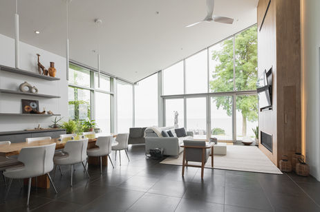 Great room with a live-edge dining table, floating shelves and a tall wood fireplace wall facing the lake