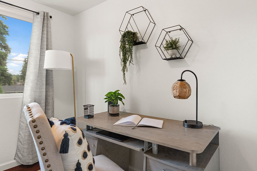 Minimalist home office with a wooden desk, open book, plants, and a wicker lamp. Hexagonal shelves with plants, large window, gray curtains.