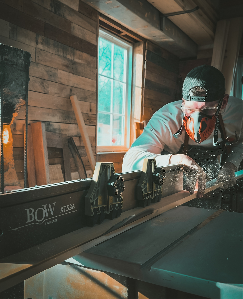 Craftsman wearing safety gear cutting wood with a table saw
