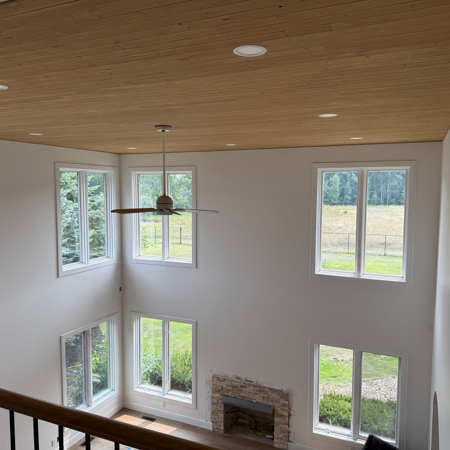High ceiling room with large windows and wood planks