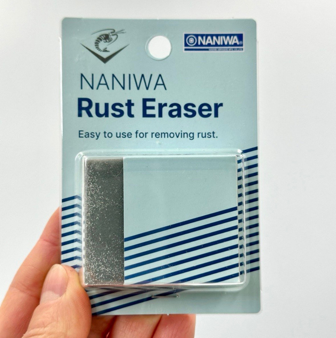 Упаковка NANIWA Rust Eraser в руке на светлом фоне, сине-голубая, надпись Easy to use for removing rust.