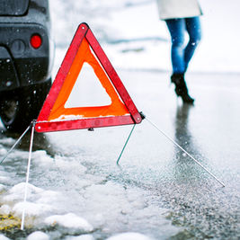 Hazard warning triangle on icy road in New Brunswick highlighting unsafe driving conditions causing school closures
