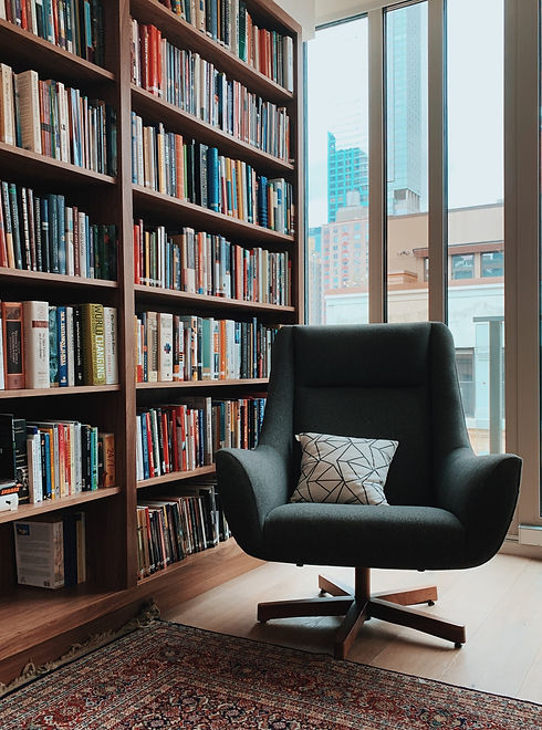 gray fabric padded rolling armchair near large book shelf