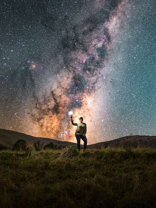Person holding light under the Milky Way galaxy night sky