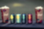 Four colourful drink cans displayed between two cartons of popcorn.