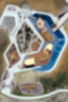 Aerial view of a playground with blue and tan play surfaces, curved paths and surrounding landscaping.