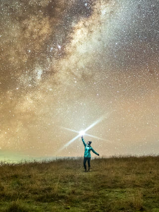 Person reaching for a bright star under the Milky Way