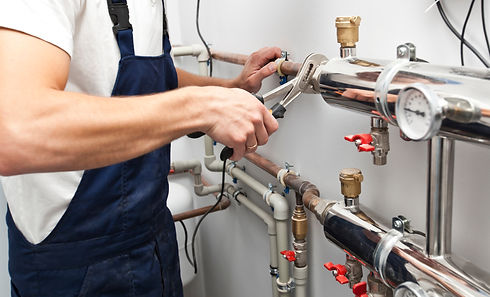 The man is installing the heater system in the house and checking pipes by the wrench.jpg