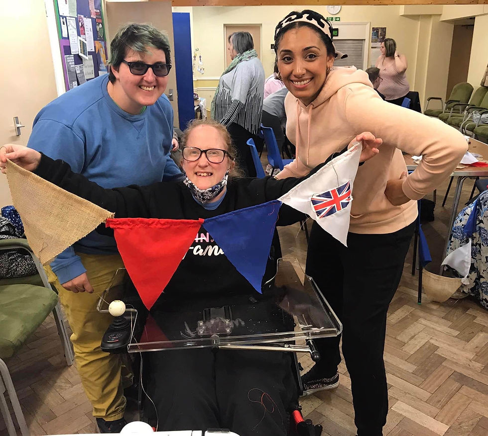 Three smiling women holding colorful bunting with a Union Jack flag.