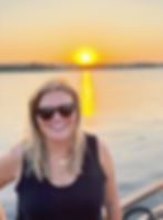 Jordan, creator of LIfetime Tidbits, standing in front of the sunset and the water