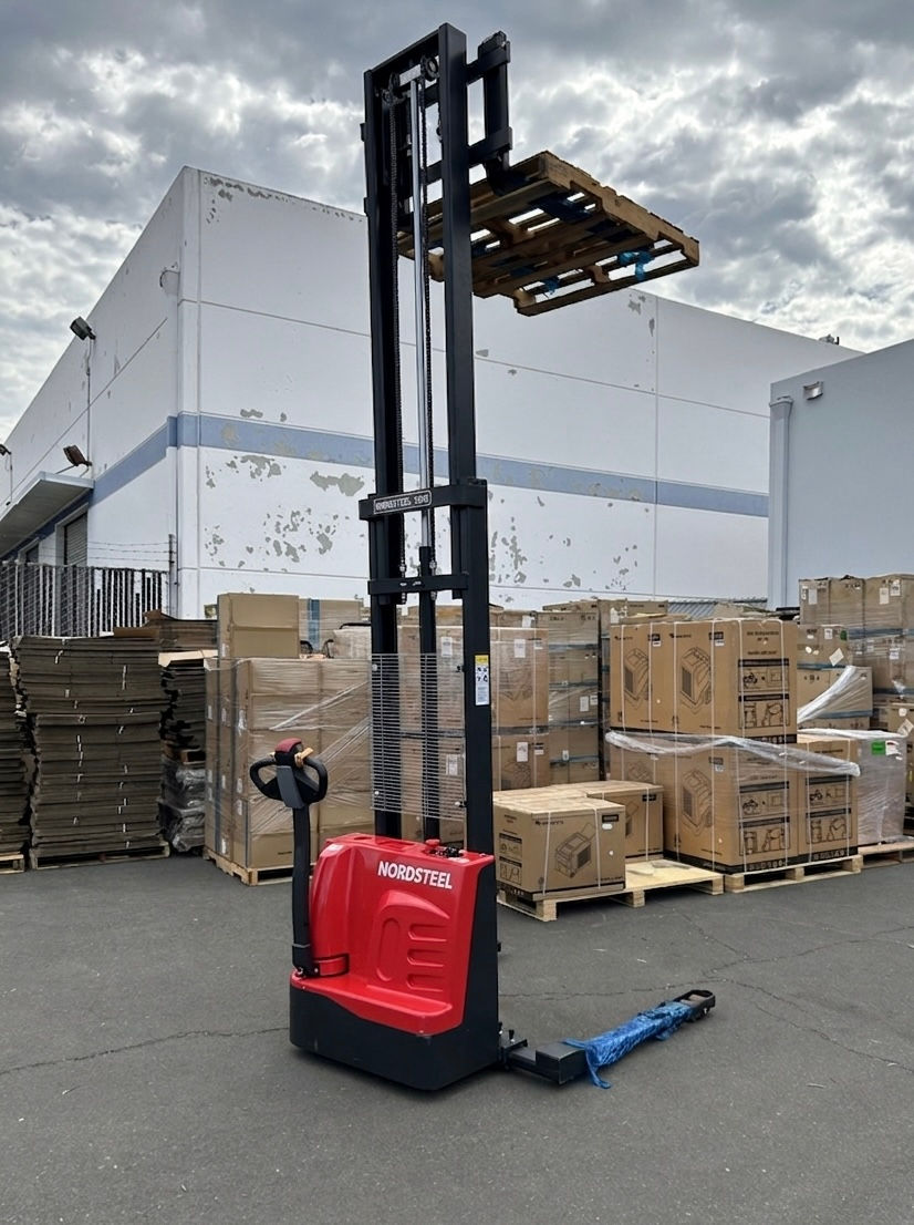 Thumbnail: Real-life action shot of the Nordsteel fully powered pallet stacker, lifting a fully loaded wooden pallet 135 inches high