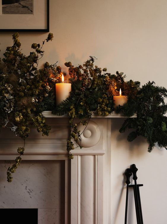 Chimenea de estilo clásico en marmol, decorada con ramas y velas. Una decoración de Navidad sencilla y elegante.