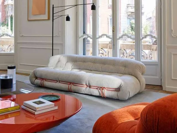 Tendencias decoración 2024. Soriana, sofá diseño original de Cassina en beige con acentos en color naranja.